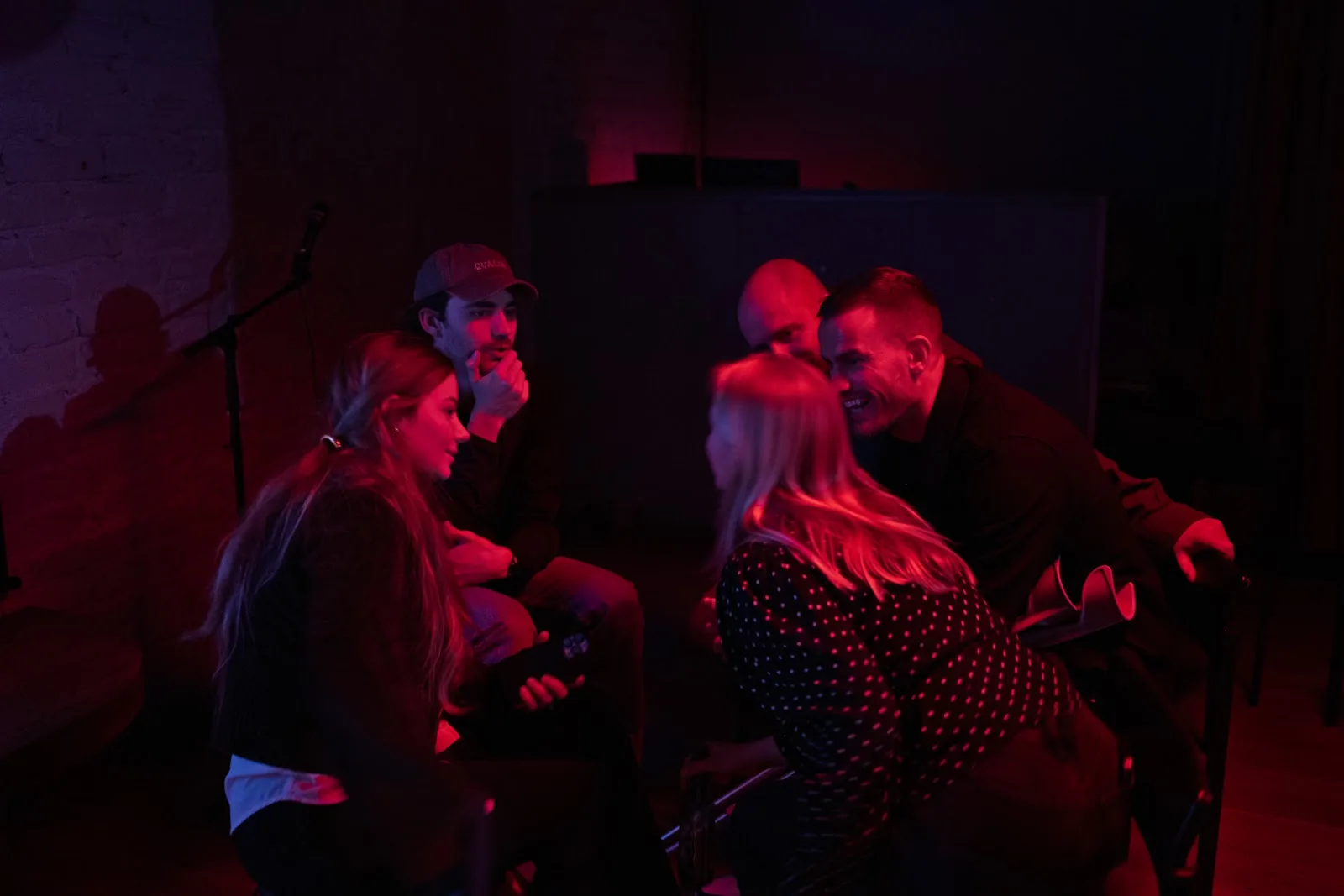 A close group talking and laughing under dark red and blue stage lighting. Helsinki.
